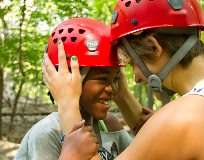 Staff and camper preparing for ropes course