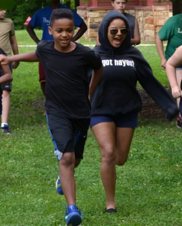 boy and girl running on field at camp